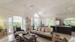 A spacious living area with a high ceiling, large windows, and a view of greenery. - Sugar Cane Ridge 23 (St James)