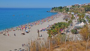 A beach with numerous umbrellas and people.