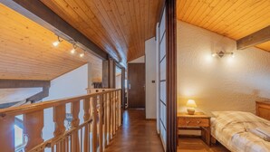 Et træpanelt interiør med en seng, et natbord og udsigt til en balkon.