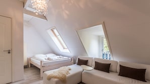 Un dormitorio moderno con techo inclinado, cama, sofá y un espejo grande.
