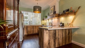 Una cocina con una isla de madera, un lámpara colgante y un ventanal con persianas.