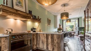 Una cocina con isla central, armarios de madera, estufa y comedor con sofá y sillas.