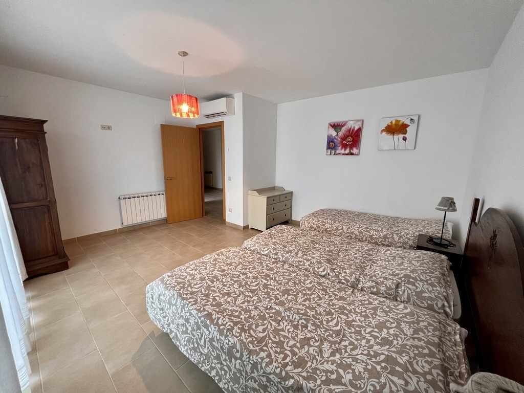 A bedroom with two beds, a wooden wardrobe, a radiator, and a door leading to another room.