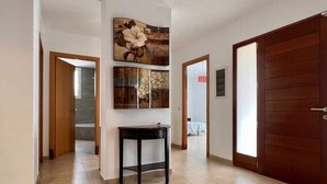 A hallway with a wooden door, a small table, and artwork on the wall. - Mas Ambros House with infinity pool and barbecues in Calonge, Girona Costa Brava (Calonge)