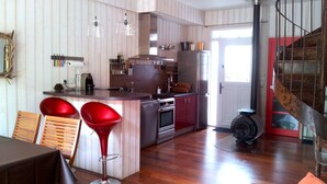 Eine moderne Küche mit Holzvertäfelung, Edelstahlgeräten und einer Kochinsel mit roten Barhocker.