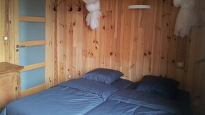 Ein Zimmer mit Holzboden, einem Bett, einem Nachttisch und einer Tür.