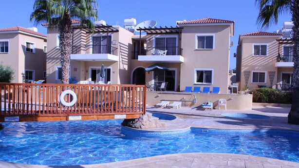 Una piscina con sillones de descanso y una terraza de madera.
