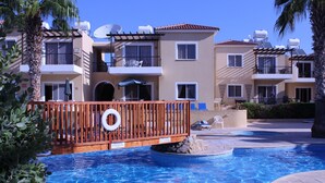 Un área de piscina con deck de madera, sillas de descanso y un flotador.