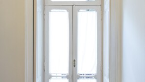 Ein Zimmer mit einer Doppeltür zu einem Flur, Holzboden und einer Heizung an der Wand.