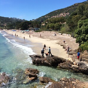 A beach with clear water, rocky areas, and people enjoying the seaside.