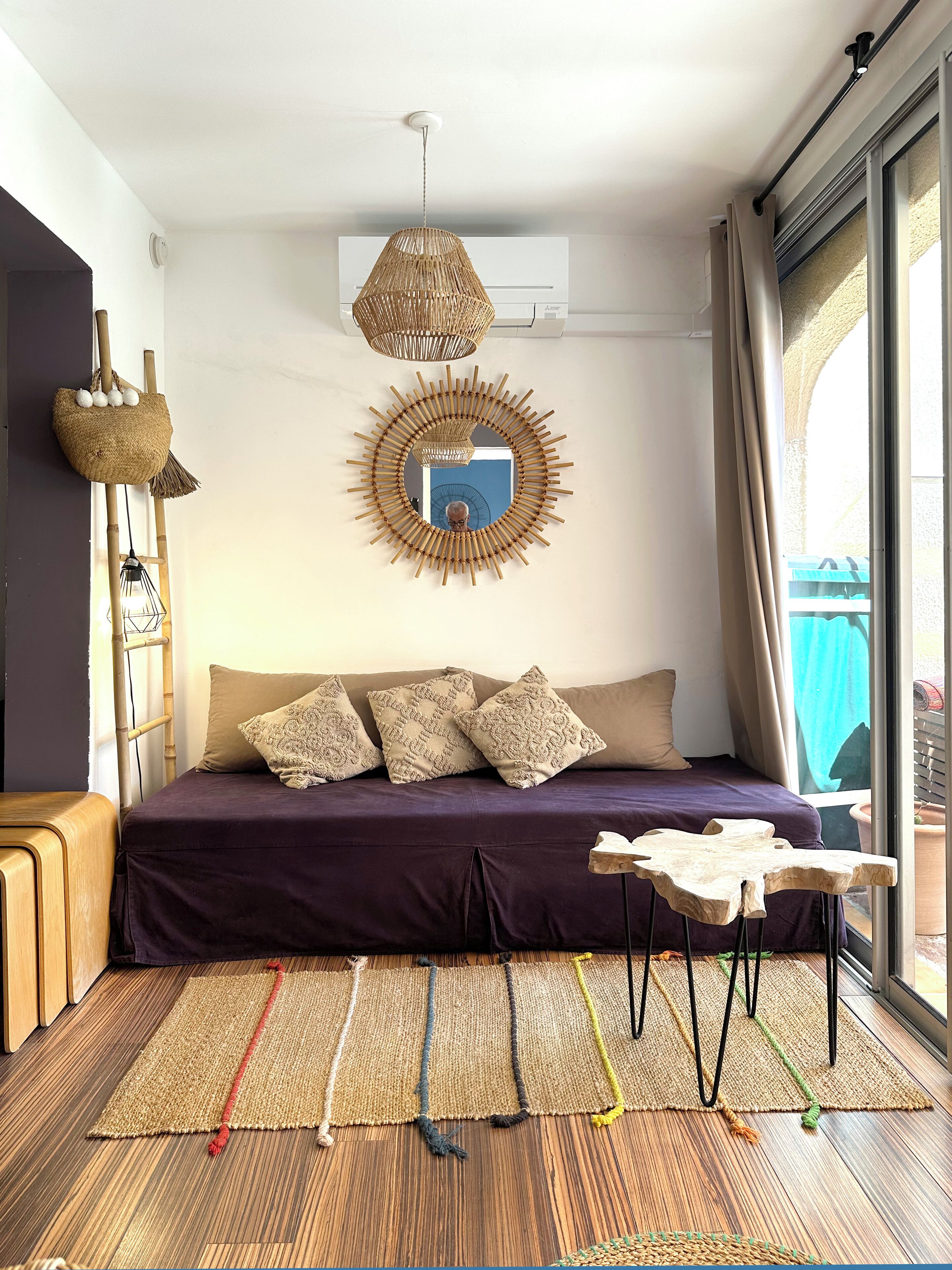 A room with a bed, a hanging light fixture, a mirror, and a window with curtains.
