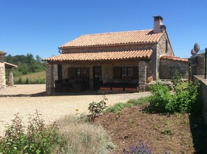 A stone building with a tiled roof, a small porch, and a gravel driveway. -  Cottage with Heated Salt water pool in private & peaceful setting. (Marthon)