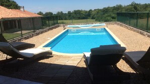 A rectangular swimming pool with a wooden deck and lounge chairs.