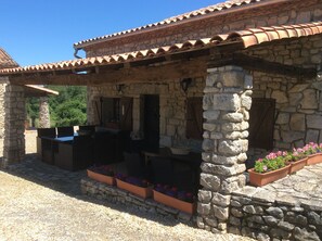 A stone building with a tiled roof, outdoor seating, and flower planters. - Cottage with Heated Salt water pool in private & peaceful setting. (Marthon)