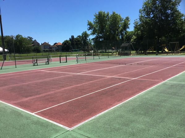 A tennis court with a green and red surface, surrounded by trees and a fence. - Cottage with Heated Salt water pool in private & peaceful setting. (Marthon)