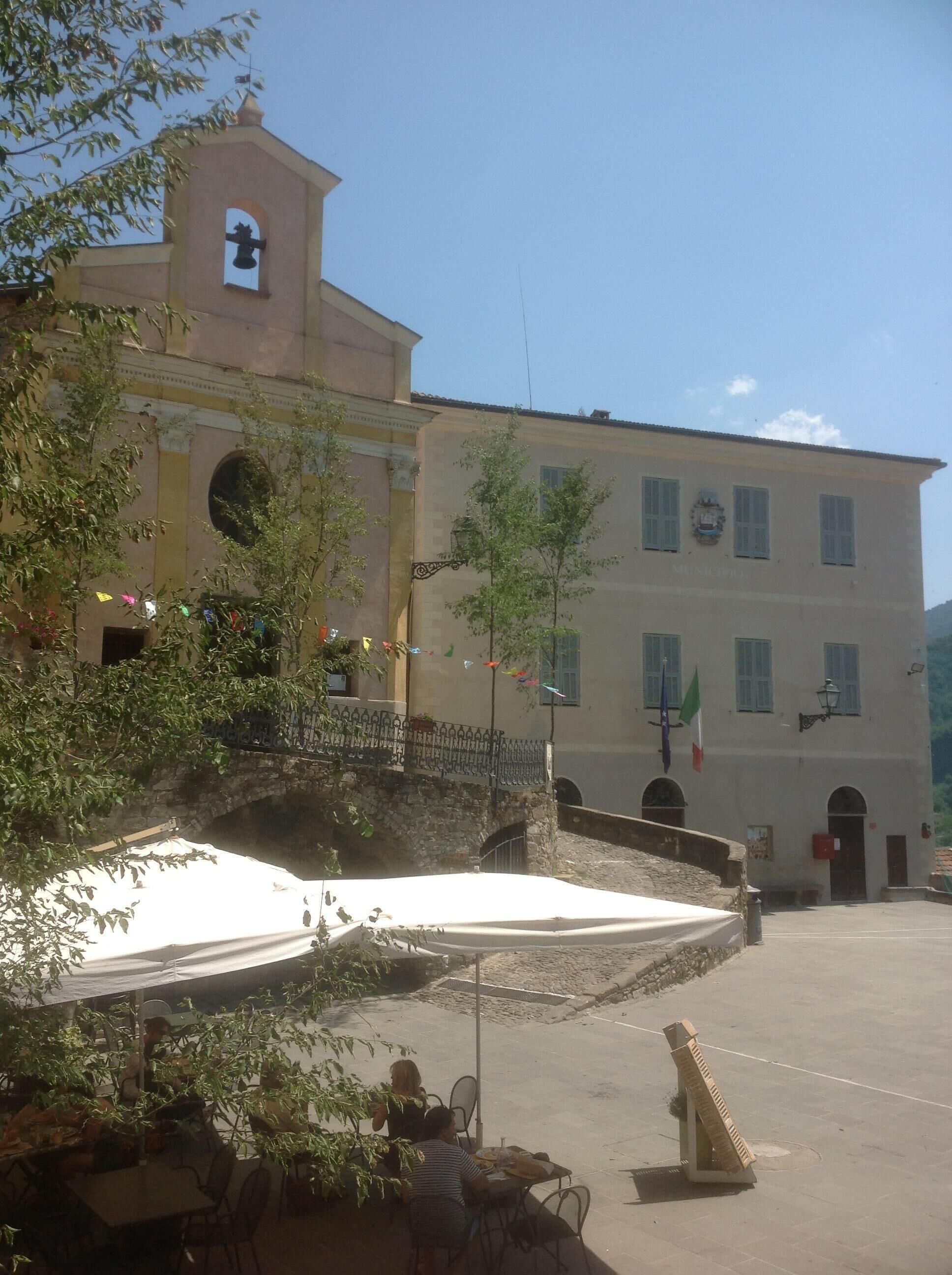 A building with a bell tower, a stone bridge, and outdoor seating.