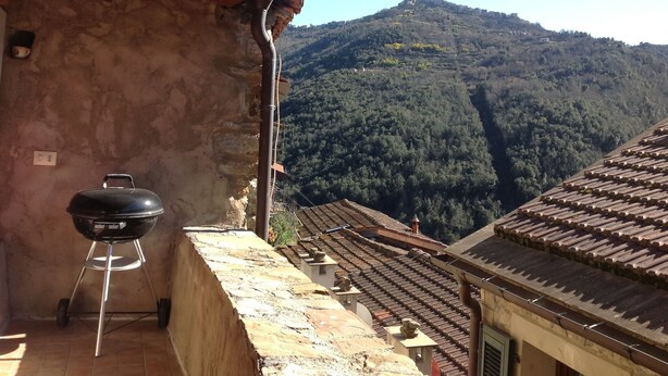 A balcony with a barbecue grill, stone walls, and a view of a forested hill. - traditional house in  beautiful APRICALE, Liguria, experience the real Italy! (Apricale)