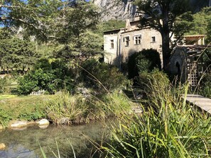 A stone building with a rustic appearance, surrounded by lush greenery and a small water feature. - Mansion - Charming cottage - SAOU (Saou)