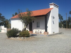 A small, single-story house with a red-tiled roof, a white exterior, and a gravel driveway. - Fantastic house w / pool in quiet and hot Alentejo plain near Évora (Montemor-o-Novo)