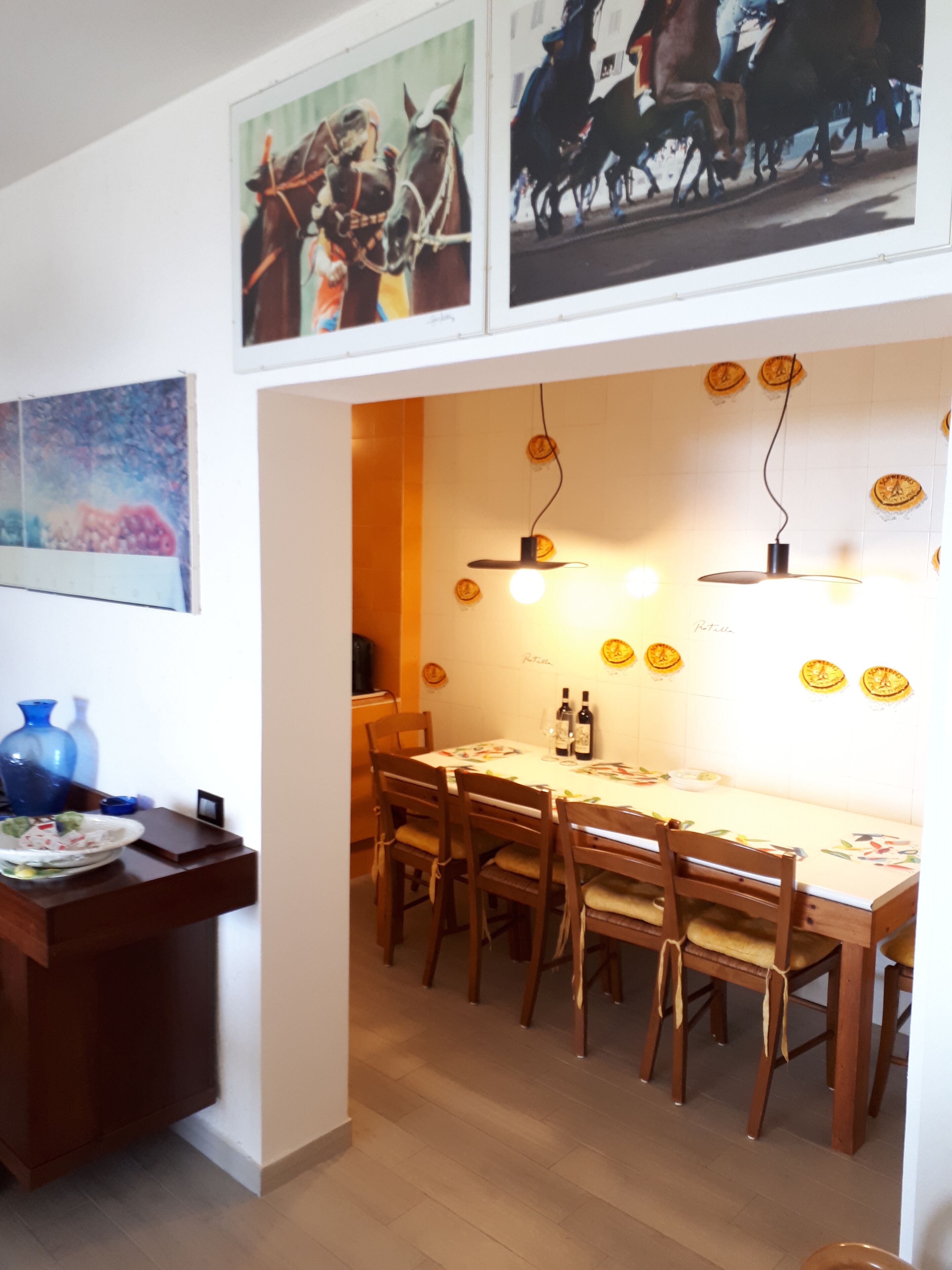 A dining area with a wooden table and chairs, a blue vase, and wall-mounted light fixtures.