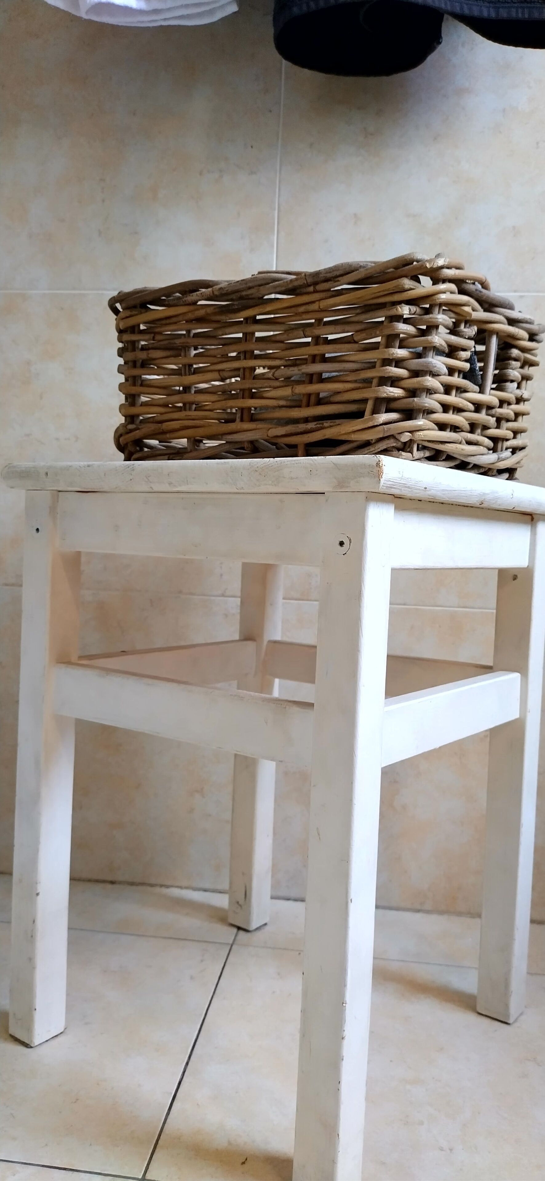 A white wooden table with a woven basket on top.
