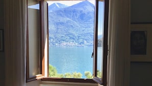 Une chambre avec une fenêtre donnant sur un lac et des montagnes.