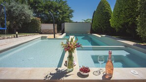A swimming pool with a bottle of champagne, a vase of flowers, and a bowl of cherries on the edge. - Heated pool, whirlpool, 3 km from the sea, barbecue, WiFi, free WLAN (Pula)