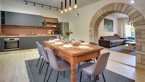 A modern kitchen with a built-in oven, a dining table set for six, and a stone archway leading to a living area with a sofa and a coffee table. - Heated pool, whirlpool, 3 km from the sea, barbecue, WiFi, free WLAN (Pula)