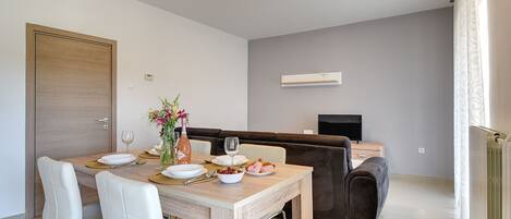 A modern dining area with a wooden table, white chairs, and a brown sofa.