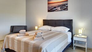 A neatly made bed with striped bedding, a headboard, and a bedside table with a lamp. - Heated pool, whirlpool, 3 km from the sea, barbecue, WiFi, free WLAN (Pula)