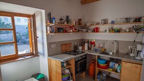 Une cuisine compacte avec des meubles en bois, un four encastré, un évier et une fenêtre donnant sur une cour.