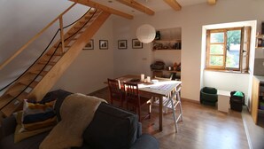 Une pièce de style « loft », avec un escalier en bois, un coin repas comprenant une table et des chaises, un canapé et une fenêtre offrant une vue.