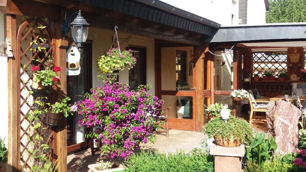 A wooden house with a garden, a hanging flower basket, and a birdhouse. - Quiet Non smoking apartment (approx 80sqm.) Located right on the edge. (Holzerath)