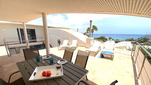 An outdoor dining area with a table set for two, overlooking a pool and the ocean. - Pool, few min from the sea, protected inner courtyard (Fuerteventura)