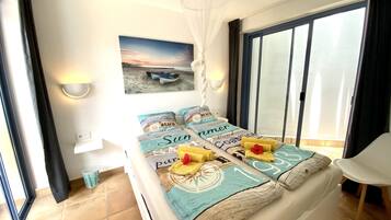 A bedroom with a bed, a view of the beach, and a chair.