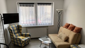 Una habitación pequeña y amoblada con sofá, sillón y una mesita.