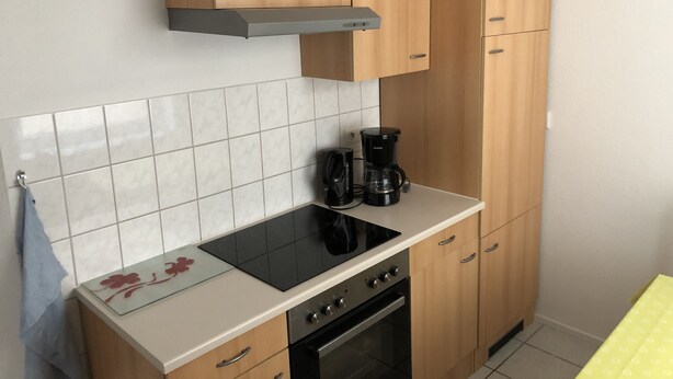 Una cocina con armarios de madera, una estufa negra y una cafetera.