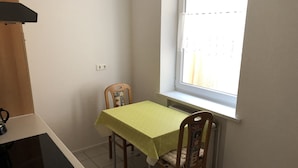 Una pequeña cocina con una mesa, sillas, una ventana y un radiador.