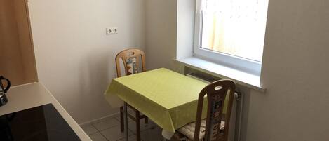 A small kitchen with a table and chairs, a window, and a radiator.