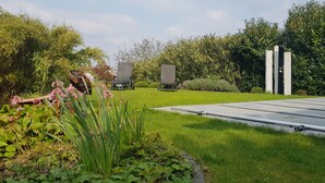 A garden with a lawn, two chairs, and a metal structure. - Comfortable apartment with pool for 2-6 people (110 sqm) (Ranschbach)