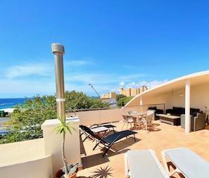 A rooftop terrace with lounge chairs, a table, and a view of the ocean and buildings. - Villa with private pool, fiber optic internet, close to the sea, sheltered courtyard (Costa Calma)