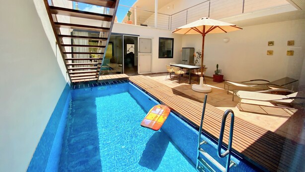 A swimming pool with a wooden deck and a glass door leading to a room. - Casa Barbara, private pool, internet, close to the ocean, sheltered courtyard/patio (Costa Calma)