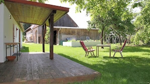 A wooden deck with a covered patio area, a table, and two chairs.