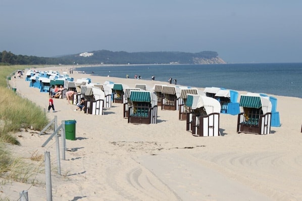 A beach with rows of beach huts along the shore.