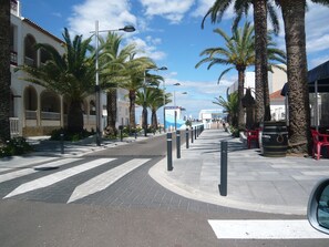 Rua com palmeiras e um edifício com janelas em arco.