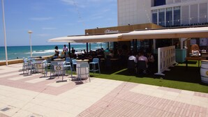 An outdoor seating area with tables and chairs, overlooking the ocean.
