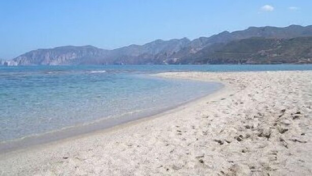 A beach with clear water and mountains in the background. - We rent whole year round indipendent Vacation house and Apartment from 2-10 pers (Italien)
