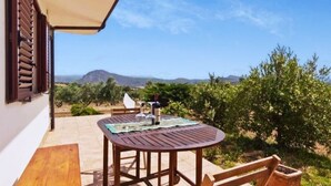 A patio with a table and chairs, a bottle of wine, and a view of the countryside. - We rent whole year round indipendent Vacation house and Apartment from 2-10 pers (Italien)