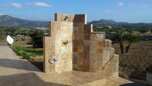 A stone structure with a water spout, surrounded by a tiled patio and a view of distant mountains. - We rent whole year round indipendent Vacation house and Apartment from 2-10 pers (Italien)