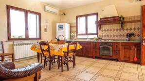 A kitchen with a dining table, chairs, a refrigerator, an oven, and a wooden door. - We rent whole year round indipendent Vacation house and Apartment from 2-10 pers (Italien)